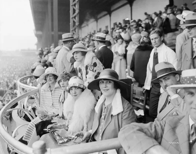 Vintage photograph of elegantly dressed women in hats and fur at the Kentucky Derby grandstand – 1920s sporting style and Derby fashion history.