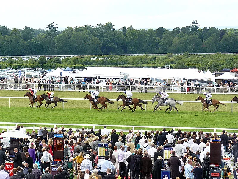 Thoroughbred horse race in progress at Royal Ascot, with a large crowd and white tents during the British social season.