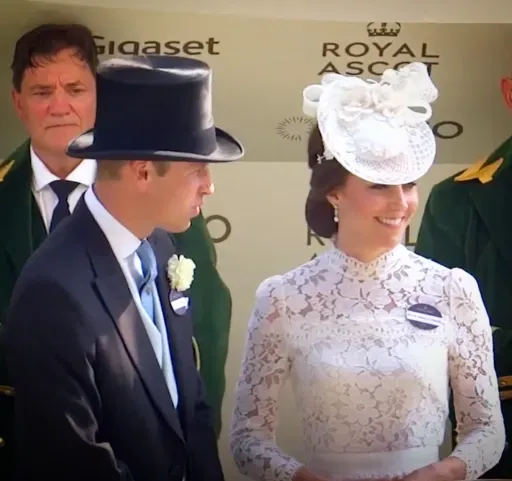Man in morning dress and woman in a white lace dress and statement hat at the Royal Enclosure, Royal Ascot.